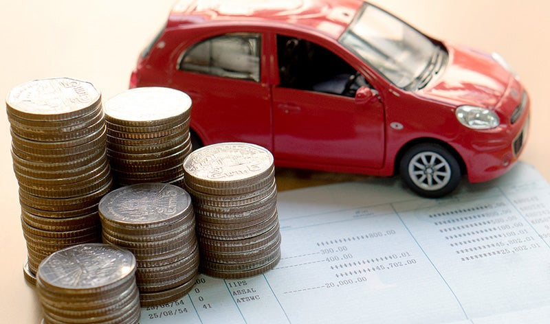 stack of coins and red toy car on book