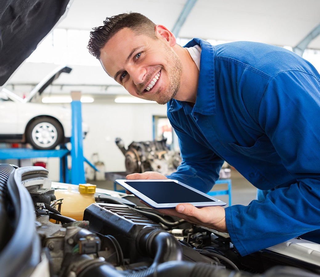 happy technician working under car hood
